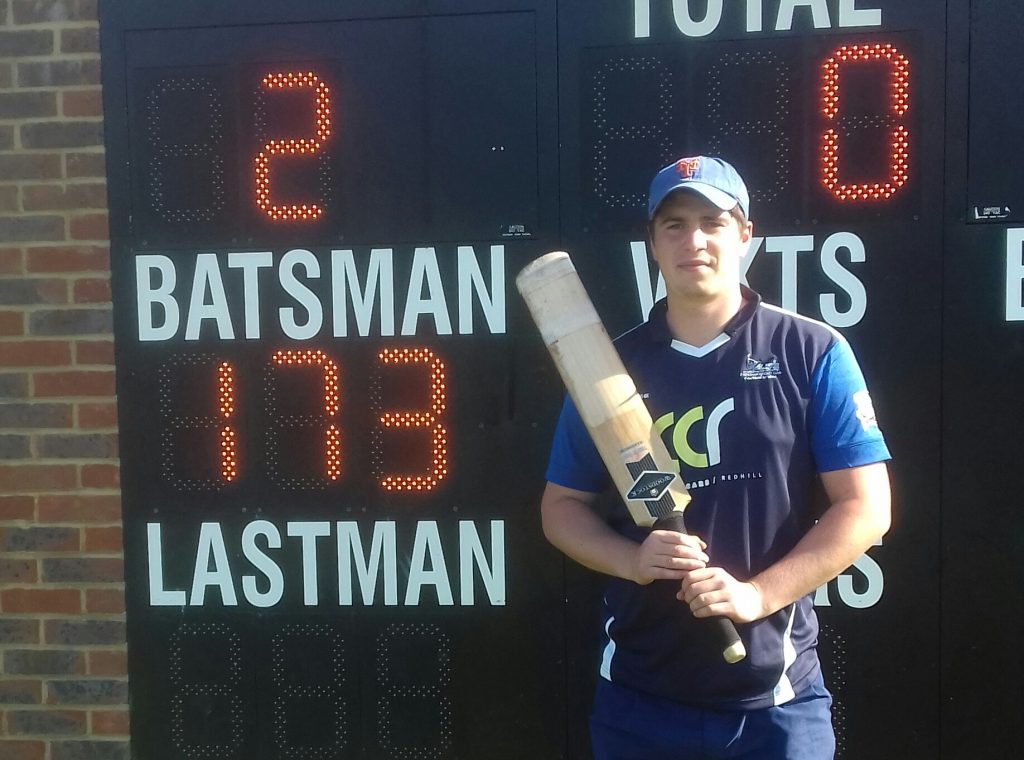 Cricketer Laurie Nicholson next to scoreboard with his record 173 score showing.