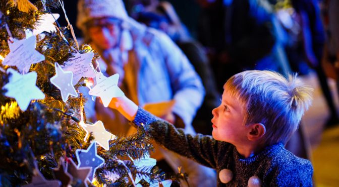 Young boy putting star onto Christmas tree